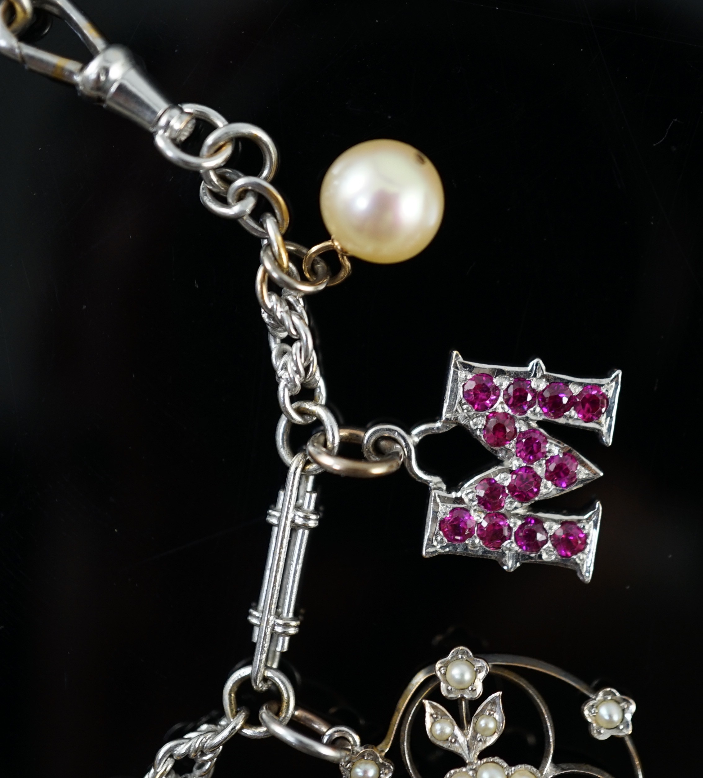 A French 18ct white gold circular and baton link charm bracelet, hung with eleven assorted charms